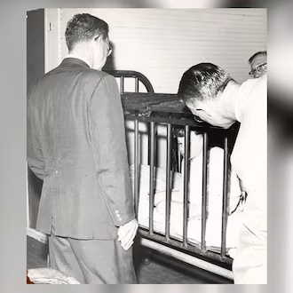 Visitors to Milledgeville State Hospital observe a small boy restrained in a metal cage in the 1940s. The Atlanta Constitution later published a series of stories about conditions at what was then one of the worldโs largest mental institutions. (AJC file)