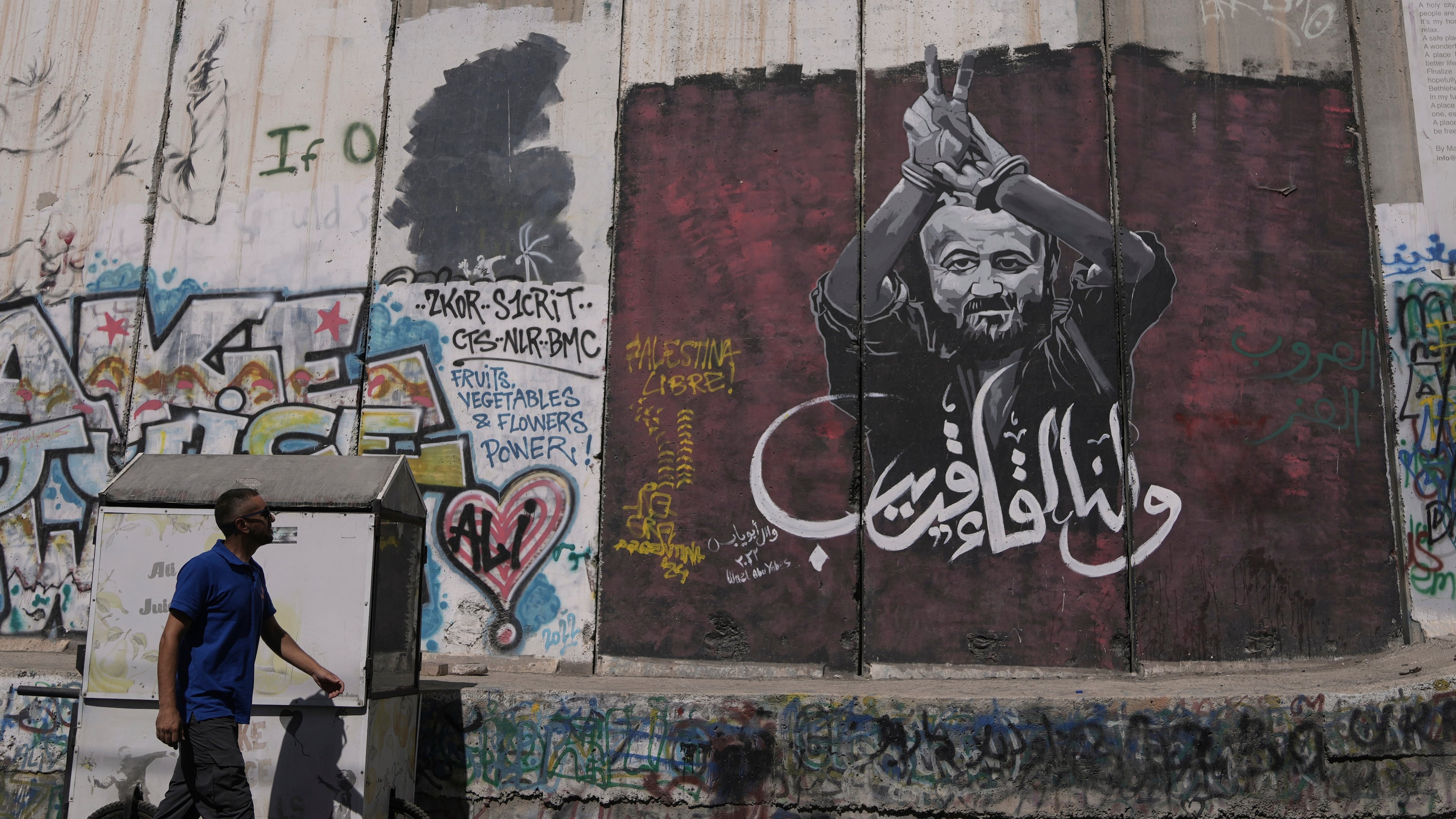 FILE - A man walks past a mural depicting the Palestinian leader Marwan Barghouti, with a message that reads in Arabic, "See you soon,” on Israel's separation barrier in the West Bank city of Bethlehem, Aug. 20, 2025. (AP Photo/Mahmoud Illean, File)