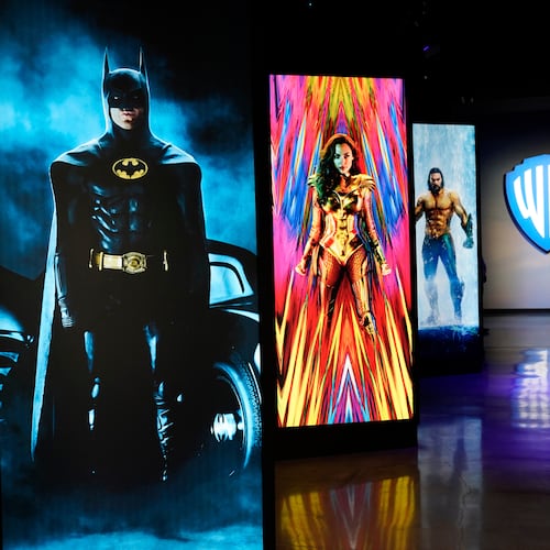 FILE - A visitor walks past portraits of DC Comics superheroes as she enters the "Action and Magic Made Here" interactive experience at the Warner Bros. Studio Tour Hollywood media preview on June 24, 2021, in Burbank, Calif. (AP Photo/Chris Pizzello, File)
