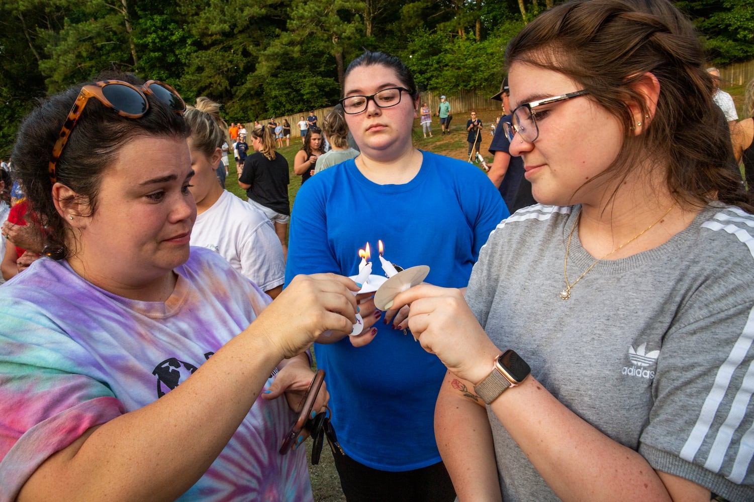Members of the Holly Springs community and neighboring police departments gather at Barrett Park for a candlelight vigil for Police Officer Joe Burson on Friday, June 18, 2021 after he was killed during a traffic stop earlier this week.  Coworkers and friends of Marykate Burson, Joe’s wife, including Katie Beganovic, left, Lisa Mayhew and Gina Ruggiero gather to mourn their friend’s husband at the candlelight vigil.  (Jenni Girtman for The Atlanta Journal-Constitution)