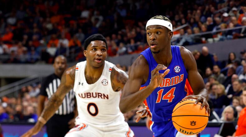 Florida guard Kowacie Reeves (14) drives to the basket around Auburn guard K.D. Johnson (0) during the first half of an NCAA basketball game Wednesday, Dec. 28, 2022, in Auburn, Ala. (AP Photo/Butch Dill)