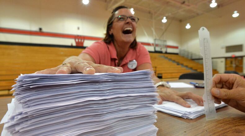 Kate Staelens reacts as she holds two stacks of "Yes" ballots on left and "No" ballots on right at Druid Hills High School on Aug. 13, 2013.