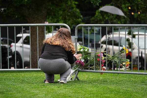 Alexandra Posnock, who moved a month ago from Skokie, Ill., to Boulder, Colo., places a bouquet of flowers along a makeshift barrier outside of the Boulder County, Colo., courthouse after Sunday's attack, Monday, June 2, 2025, in Boulder, Colo. (AP Photo/David Zalubowski)