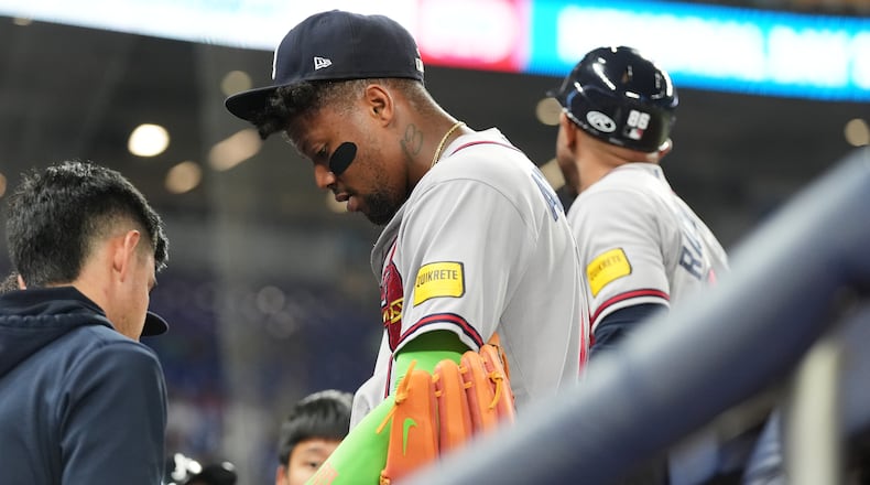 Atlanta Braves' Ronald Acuna, center, has his finger looked at during the fifth inning of a baseball game against the Miami Marlins, Thursday, May 21, 2026, in Miami. (Lynne Sladky/AP)