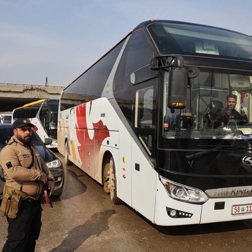 Members of Syrian government forces stand around buses prepared to evacuate Kurdish militants, under escort to the country's northeast, controlled by the SDF, after a ceasefire was announced following days of clashes in the northern city of Aleppo, Syria, Friday, Jan. 9, 2026. (AP Photo/Omar Albam)