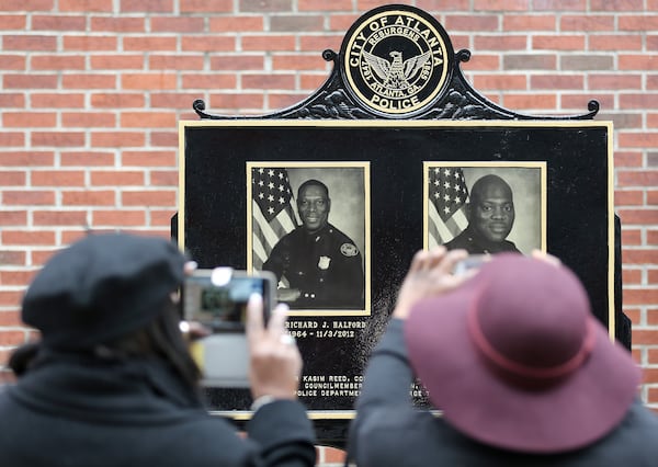 Family members photograph a memorial to Atlanta police officers Richard Halford and Shawn Smiley following a dedication ceremony on Wednesday, Jan. 20, 2016, at police headquarters. The two officers died in a 2012 helicopter crash. (Ben Gray for the AJC)