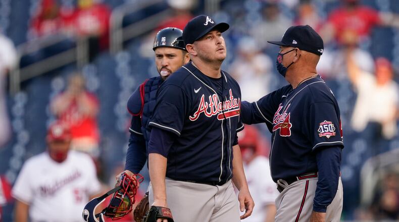 Atlanta Braves relief pitcher Tyler Matzek walks off the field after being relieved by Atlanta Braves manager Brian Snitker, right, in the seventh inning of an opening day baseball game against the Washington Nationals at Nationals Park, Tuesday, April 6, 2021, in Washington. (AP Photo/Alex Brandon)