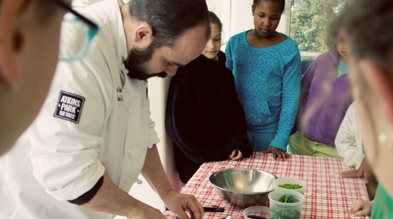 Chef Andrew Smith of Atkins Park restaurant shows students from Springdale Park elementary how to prepare produce raised in the school's gardens. Credit:Jenna Mobley.
