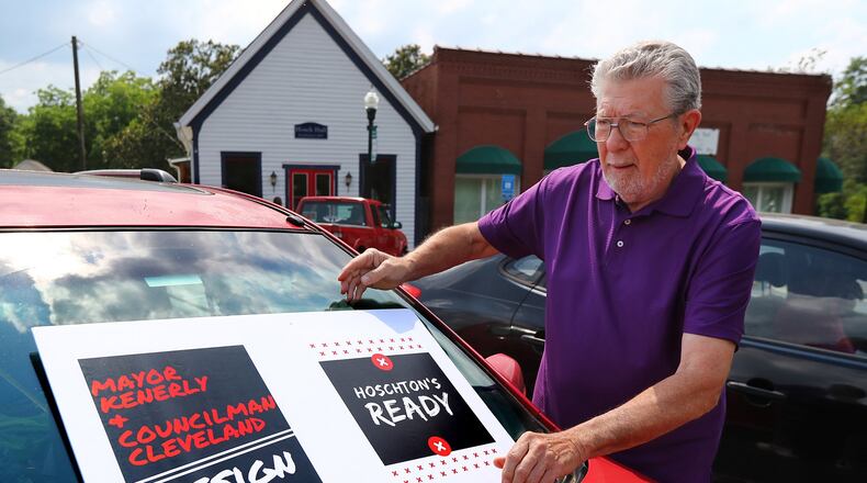 Hoschton resident Russ Zyga puts a sign on his car in front of City Hall Wednesday. The Jackson County Democratic and Republican parties were holding a joint event nearby to show residents how to file ethics complaints against two city officials whose racially charged remarks drew criticism nationwide. CURTIS COMPTON/ccompton@ajc.com