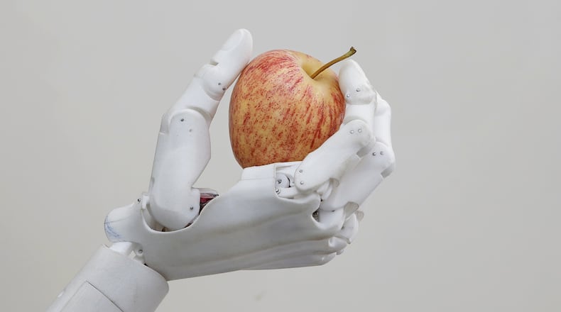 In this Sept. 28, 2017, photo, Hanson Robotics' flagship robot Sophia, a lifelike robot powered by artificial intelligence, holds an apple in Hong Kong. Sophia is a creation of the Hong Kong-based startup working on bringing humanoid robots to the marketplace. Founder David Hanson envisions a future in which AI-powered robots evolve to become super-intelligent genius machines that can help solve mankinds most challenging problems.