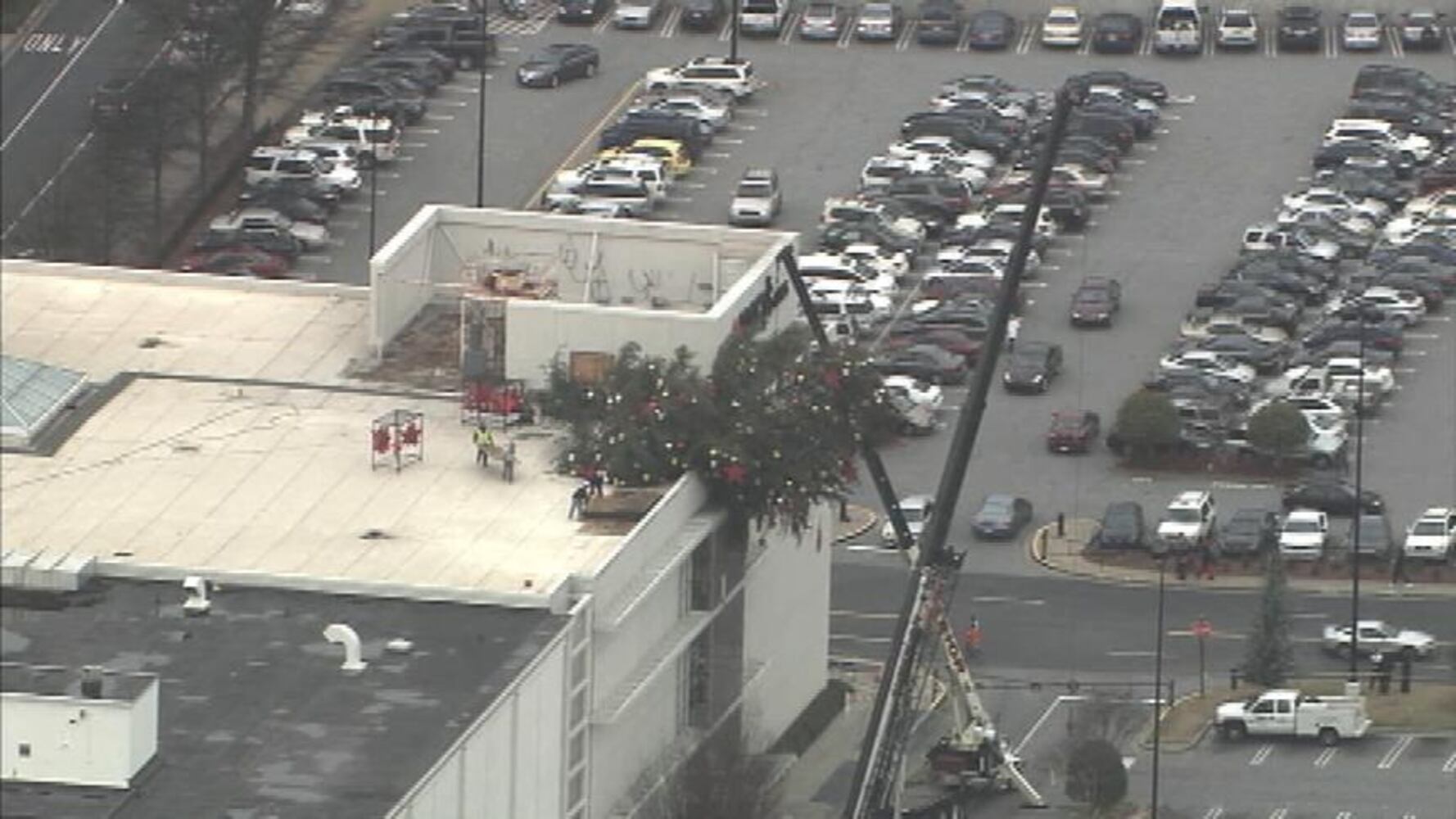 Crane buckles, leaving Christmas tree hanging off roof