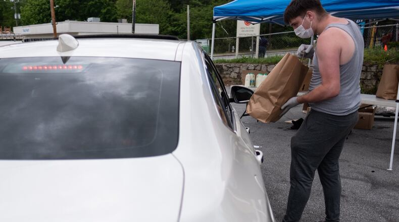 Stephen Tate gives a bag of food to a person at the CHRIS 180 drive-up food distribution April 24, 2020. The organization is making 600 food deliveries twice a week and has also started allowing people to drive up and receive food. Ben@BenGray.com for The Atlanta Journal-Constitution