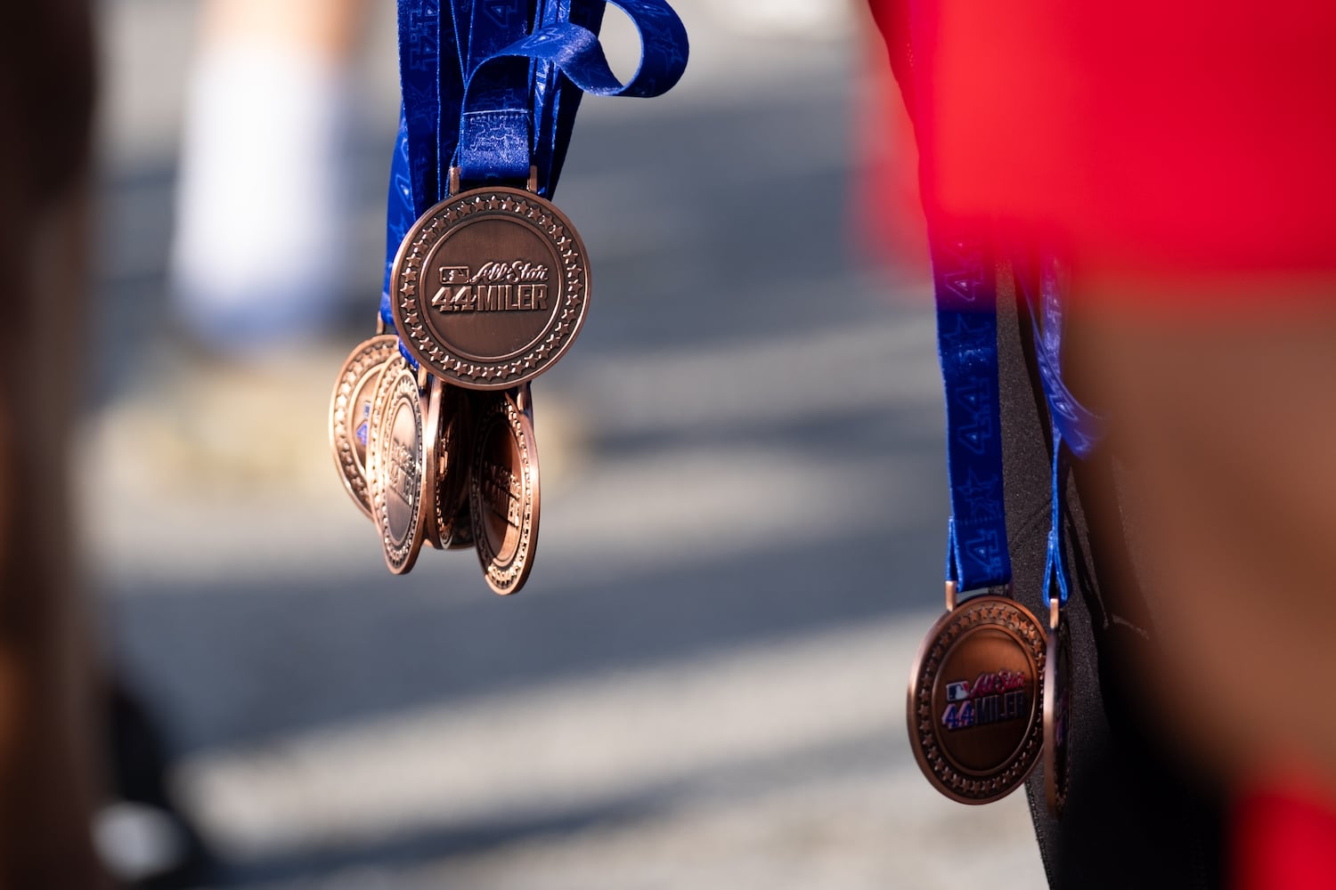 A volunteer hands out participation medals at the finish line of the MLB All-Star 4.4 Miler in Atlanta on Sunday, July 13, 2025.   Ben Gray for the Atlanta Journal-Constitution