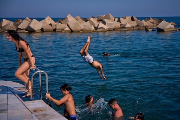 Swimmers jump into the water on a hot day in Barcelona, Spain, Tuesday, July 1, 2025. (AP Photo/Emilio Morenatti)