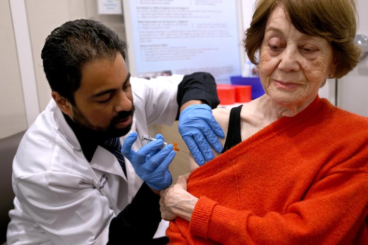 Dr. Gaurav Shinde (left) gives Giti Noroozi, 85, vaccinations for COVID and the flu at a California pharmacy in 2024. It is recommended that older adults get flu shots, as they are at a higher risk for hospitalization or death from the flu. (Genaro Molina/TNS 2024)