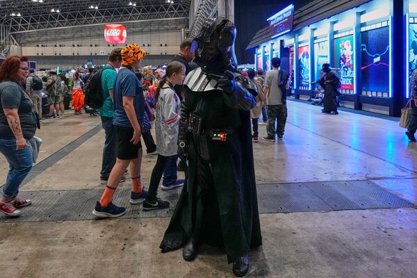 A Star Wars fan dressed as Darth Vader tries to demonstrate the Force during a fan convention called the Star Wars Celebration Japan in Chiba, near Tokyo, Friday, April 18, 2025. (AP Photo/Hiro Komae)