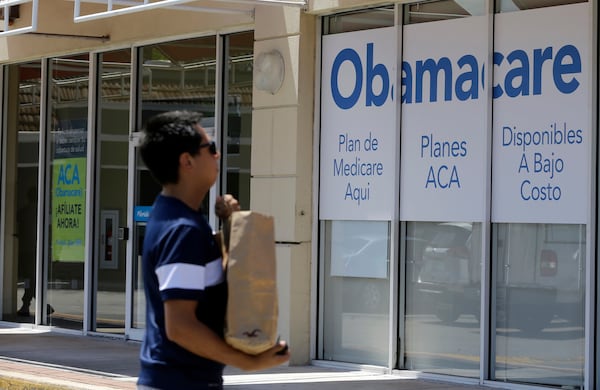 A man walks by a healthcare insurance office in Hialeah, Fla., in 2017. (Alan Diaz/AP)