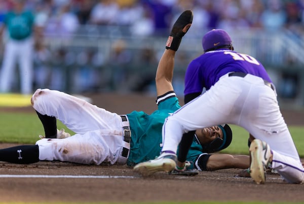 LSU's Michael Braswell III, top right, tags out Coastal Carolina's Sebastian Alexander, bottom, on an attempt to steal third base in the third inning of Game 1 of the NCAA College World Series baseball finals in Omaha, Neb., Saturday, June 21, 2025. (AP Photo/Rebecca S. Gratz)