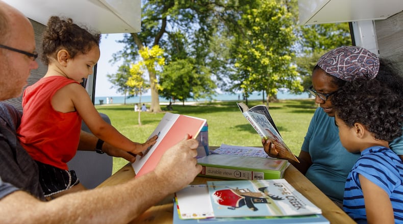 Thomas Kubik reads to Adair, 2, and Tiana Kubik reads to Griffin, 6, on Tuesday, July 23, 2019 inside their van while parked at Montrose Harbor. (Brian Cassella/Chicago Tribune/TNS)