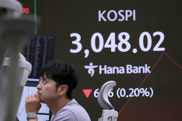 A currency trader watches monitors near a screen showing the Korea Composite Stock Price Index (KOSPI) at the foreign exchange dealing room of the KEB Hana Bank headquarters in Seoul, South Korea, Monday, July 7, 2025. (AP Photo/Ahn Young-joon)