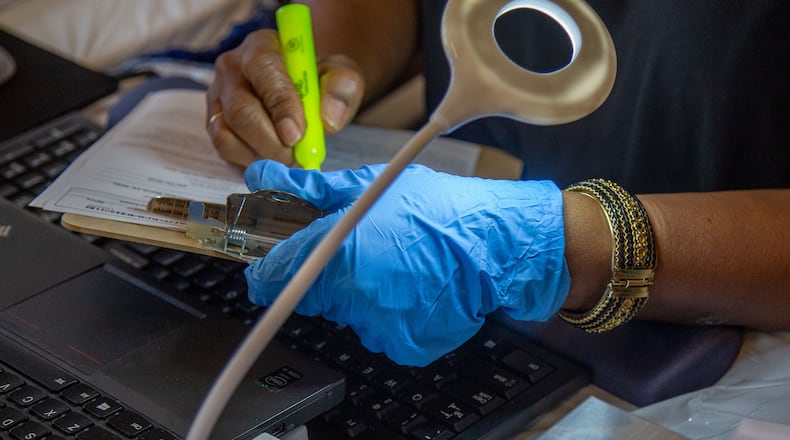 Poll worker Jumaine Russell looks over an advanced early voting form at Johns Creek polling station  Saturdays March 14, 2020.  STEVE SCHAEFER / SPECIAL TO THE AJC