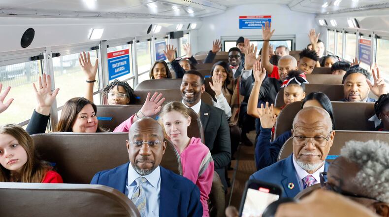 U.S. Sen. Raphael Warnock, D-Ga., and Environmental Protection Agency Administrator Michael S. Regan (two rows behind) enjoy a test ride on an electric bus in DeKalb County on Monday, Jan. 8, 2024. The school district will receive a $20 million federal grant to buy electric buses. (Miguel Martinez /miguel.martinezjimenez@ajc.com)