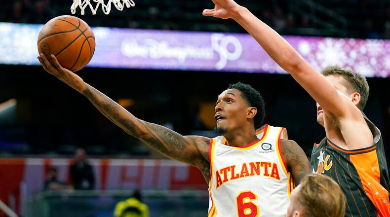 Atlanta Hawks guard Lou Williams (6) gets past Orlando Magic center Moritz Wagner, right, for a shot during the first half of an NBA basketball game, Wednesday, Dec. 15, 2021, in Orlando, Fla. (AP Photo/John Raoux)