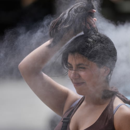 FILE - A person cools off at a cooling mist spot on a hot and sunny day at the Sensoji Buddhist temple in Tokyo's Asakusa district on Aug. 7, 2026. (AP Photo/Eugene Hoshiko, File)