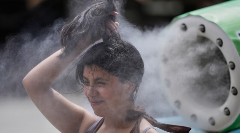 FILE - A person cools off at a cooling mist spot on a hot and sunny day at the Sensoji Buddhist temple in Tokyo's Asakusa district on Aug. 7, 2026. (AP Photo/Eugene Hoshiko, File)