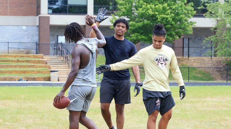 Camren Jackson (middle) and Kaece Supples (right) give high-fives to Keeman Hayes (left) in between one-on-ones during an unsanctioned player-led football practice on Thursday, June 4, 2020, at Tucker High School in Tucker, Georgia. The players planned the off-season practice despite uncertainty surrounding the upcoming football season amid coronavirus concerns. CHRISTINA MATACOTTA FOR THE ATLANTA JOURNAL-CONSTITUTION