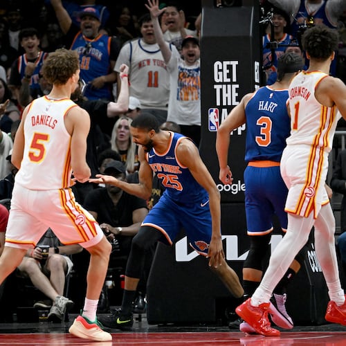 Knicks guard Mikal Bridges (center), flanked by the Hawks’ Dyson Daniels (left) and Jalen Johnson, celebrates after dunking the ball during Game 6 of the first-round Eastern Conference series at State Farm Arena on Thursday, April 30, 2026, in Atlanta. (Hyosub Shin/AJC)