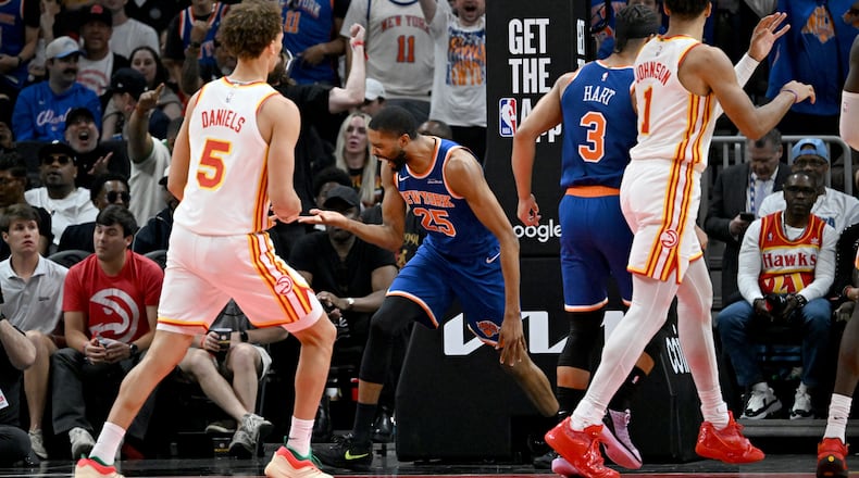 Knicks guard Mikal Bridges (center), flanked by the Hawks’ Dyson Daniels (left) and Jalen Johnson, celebrates after dunking the ball during Game 6 of the first-round Eastern Conference series at State Farm Arena on Thursday, April 30, 2026, in Atlanta. (Hyosub Shin/AJC)