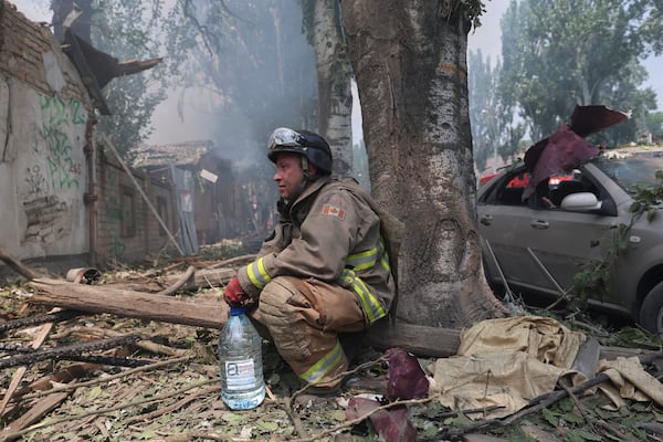 A rescue worker rests as others put out a fire of a building destroyed by a Russian drone strike in Zaporizhzhia, Ukraine, on Monday, July 7, 2025. (AP Photo/Kateryna Klochko)