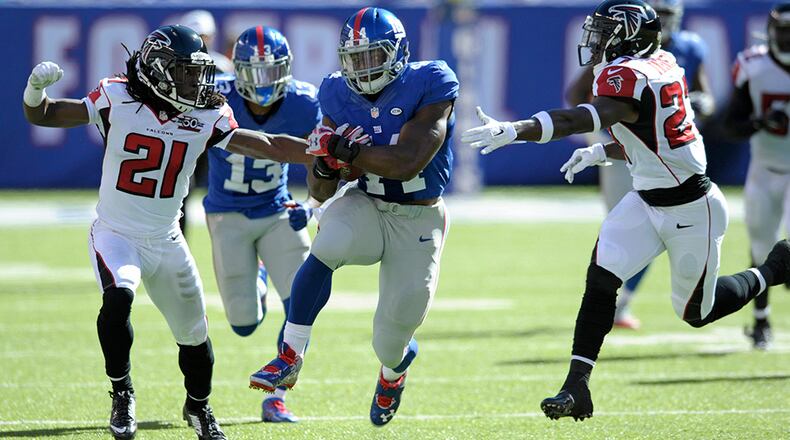 New York Giants running back Andre Williams (44) runs between Falcons cornerback Desmond Trufant (21) and Robenson Therezie.