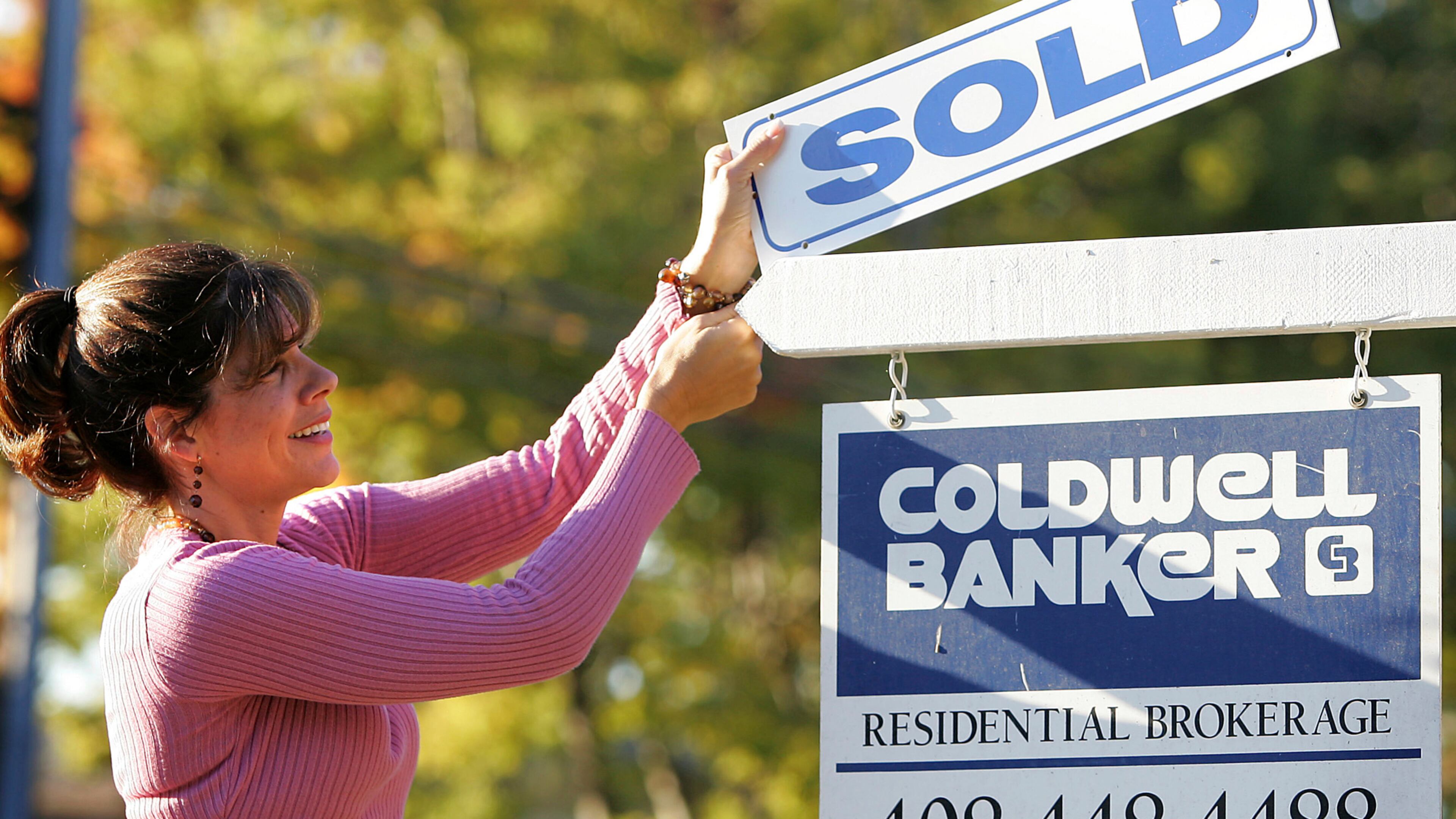 FILE - Coldwell Banker realtor Suzanne Hunter puts a sold sign on a home that she sold in Santa Clara, Calif., on Oct. 7, 2007. (AP Photo/Tony Avelar, File)