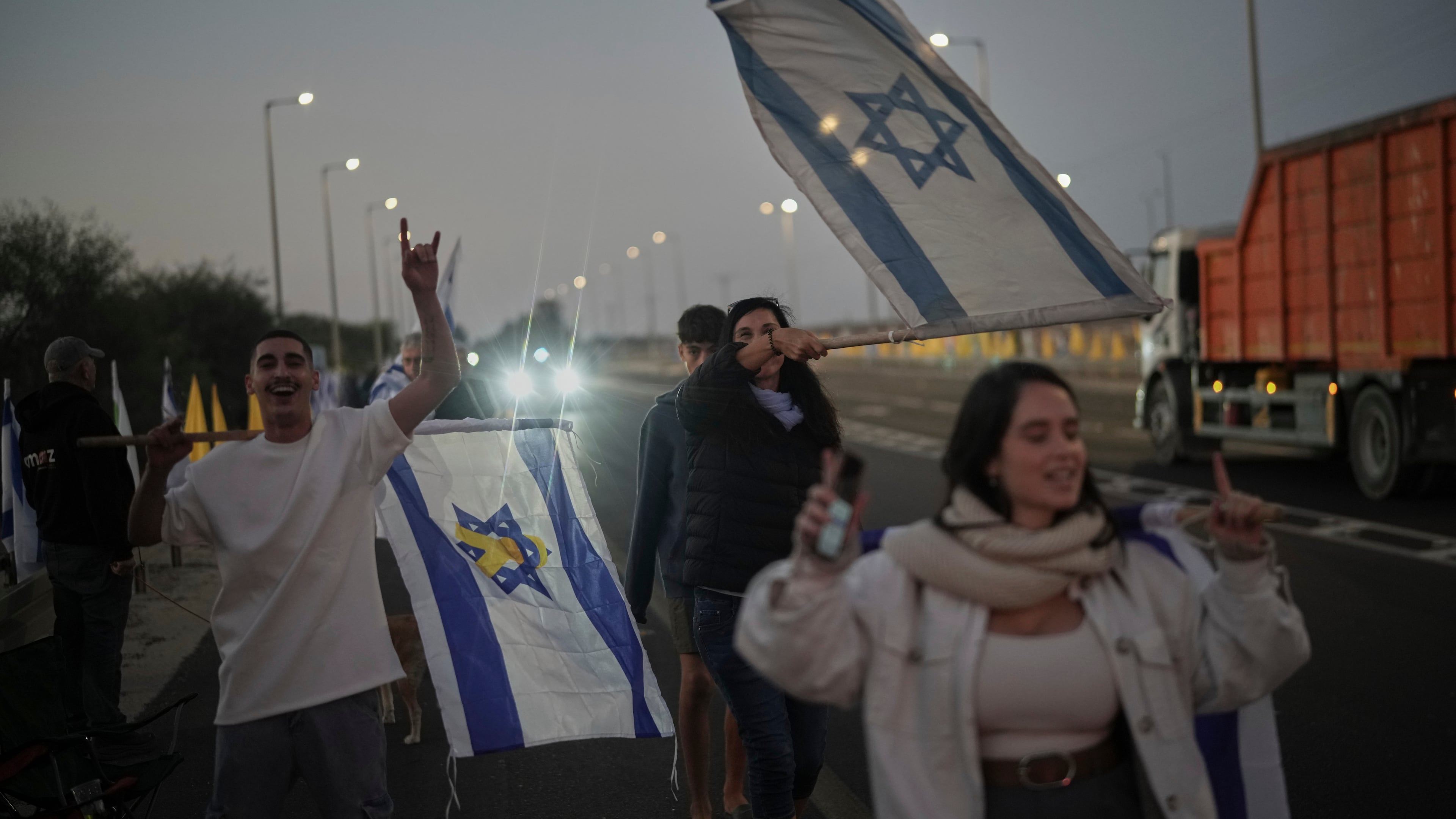 People hold Israeli flags as they gather prior to the release of Israeli hostages held in Gaza, in front of a military base near Reim Area, southern Israel, on Monday, Oct, 13, 2025. (AP Photo/Leo Correa)