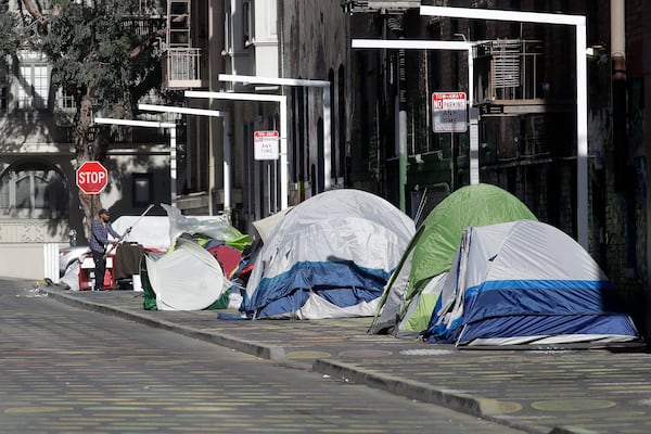 FILE - A man stands next to tents on a sidewalk in San Francisco on April 21, 2020. (AP Photo/Jeff Chiu, File)