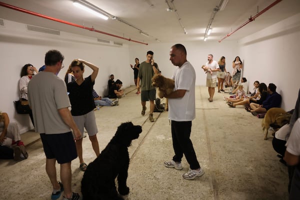 People take shelter as a siren sounds a warning following a missiles that were launched from Iran, in Tel Aviv, Israel, on Friday, June 13, 202 5. (AP Photo/Tomer Appelbaum)