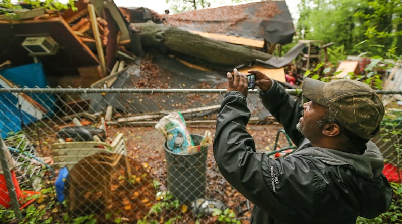 Damon Sylve takes photos of the tree that crashed down onto his family’s southwest Atlanta home early Friday. JOHN SPINK / JSPINK@AJC.COM