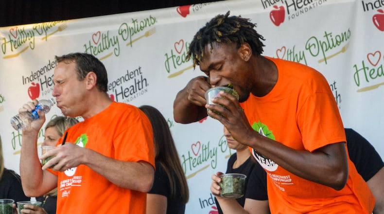 Two-time kale eating champion Gideon Oji, right, downs a container of the leafy green vegetable, while hot-dog-eating champ Joey Chestnut, left, takes a drink of water during Sunday's Kale Yeah! Competition at the Erie County Fair in Hamburg, N.Y.