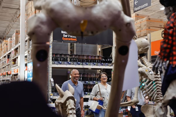 Derek King and his wife, Jennifer, look up at "Skelly," Home Depot’s 12-foot skeleton, at the Vinings location on Monday, Sept. 29, 2025. The oversized Halloween decoration is a seasonal favorite for shoppers. (Natrice Miller/AJC)