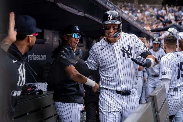 New York Yankees' Aaron Judge (99) celebrates in the dugout after hitting a grand slam in the third inning of a baseball game against the Milwaukee Brewers, Saturday, March 29, 2025, in New York. (AP Photo/Angelina Katsanis)