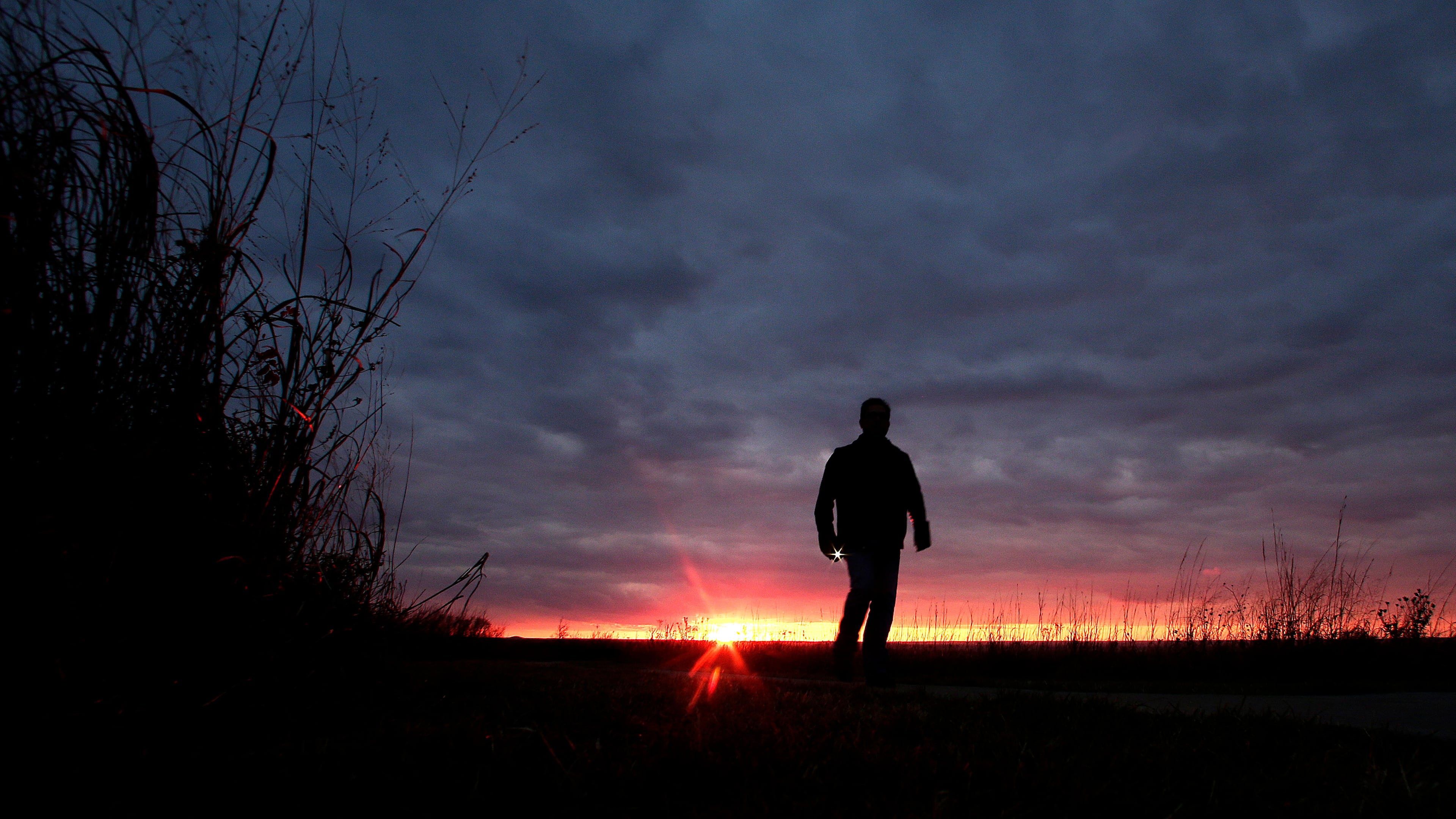 FILE - A man walks along a trail during sunset near Manhattan, Kan., on Nov. 20, 2015. (AP Photo/Charlie Riedel, File)