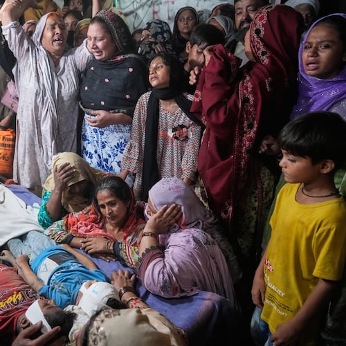 Women mourn next to the bodies of their children killed after the roof of a tutoring center under-construction collapsed, on the outskirts of Lahore, Pakistan, Tuesday, June 30, 2026. (AP Photo/K.M Chaudary)