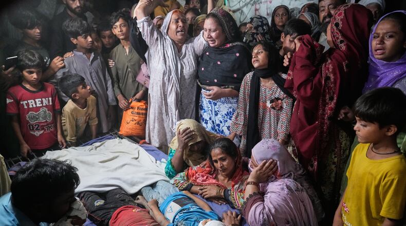 Women mourn next to the bodies of their children killed after the roof of a tutoring center under-construction collapsed, on the outskirts of Lahore, Pakistan, Tuesday, June 30, 2026. (AP Photo/K.M Chaudary)
