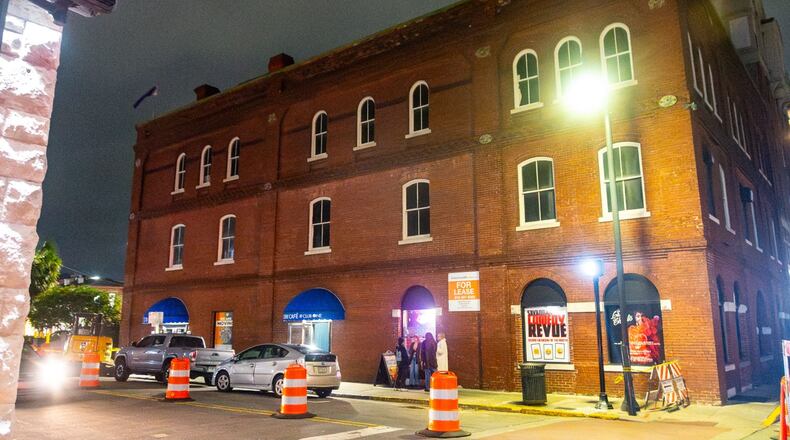 An old brick industrial building with a street lamp in front of it lighting it at night.