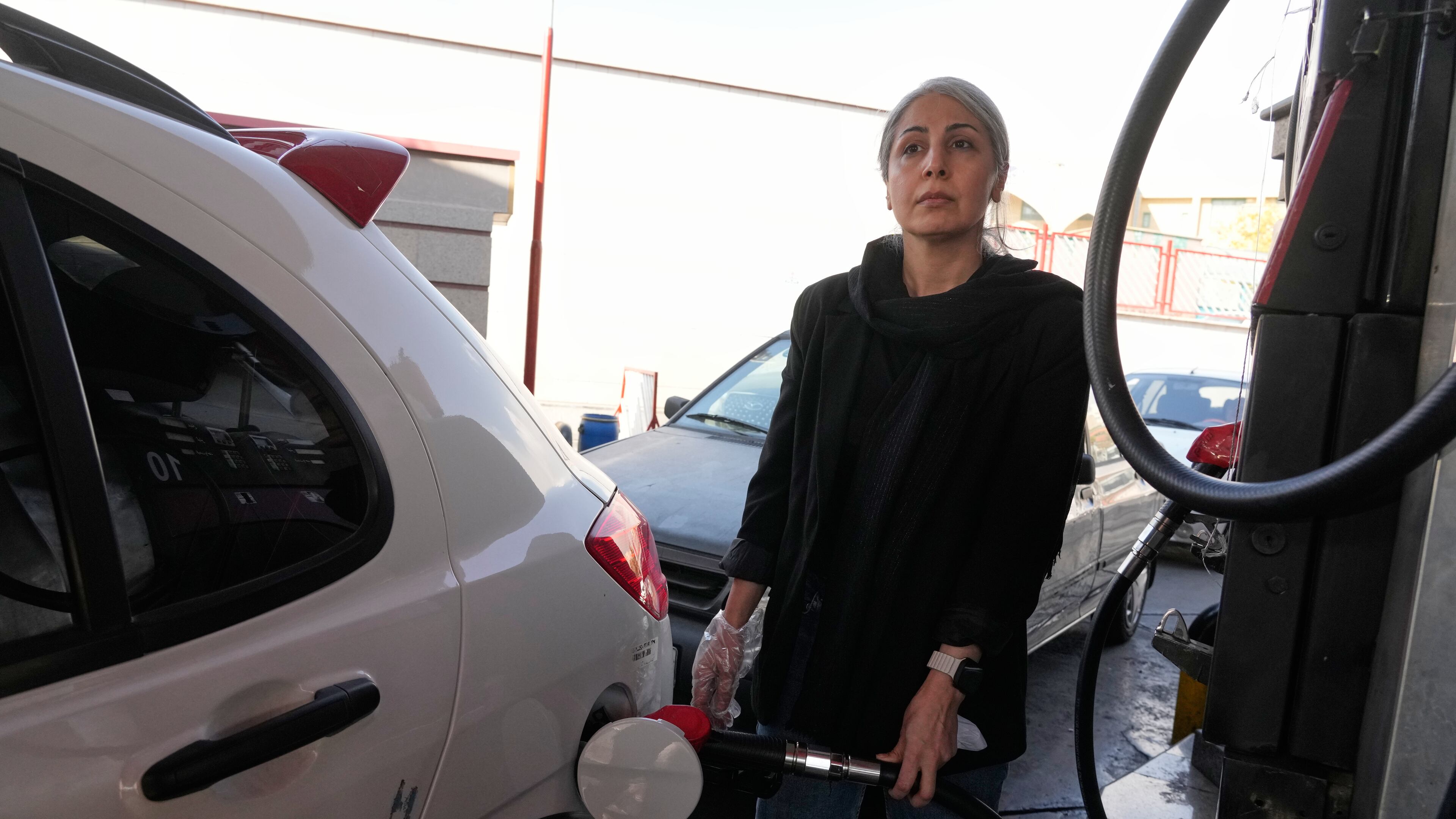 A woman fills her car at a gas station in Tehran, Iran, Thursday, Nov. 27, 2025. (AP Photo/Vahid Salemi)
