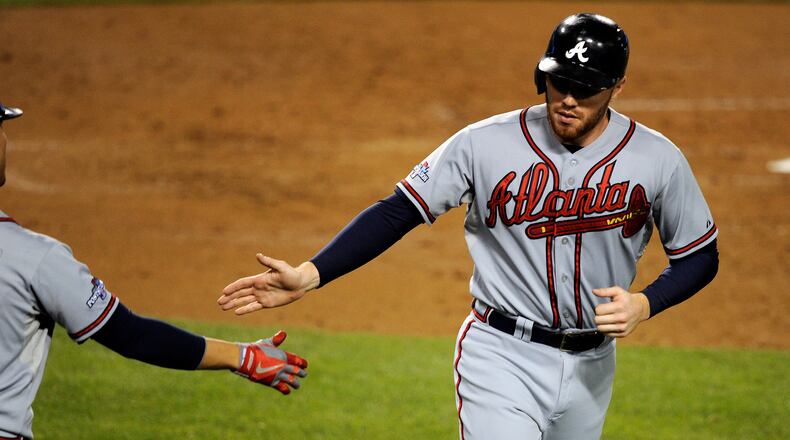 Atlanta Braves first baseman Freddie Freeman (5) is congratulated after scoring a run in the fourth inning against the Los Angeles Dodgers in game four of the National League divisional series playoff baseball game at Dodger Stadium.