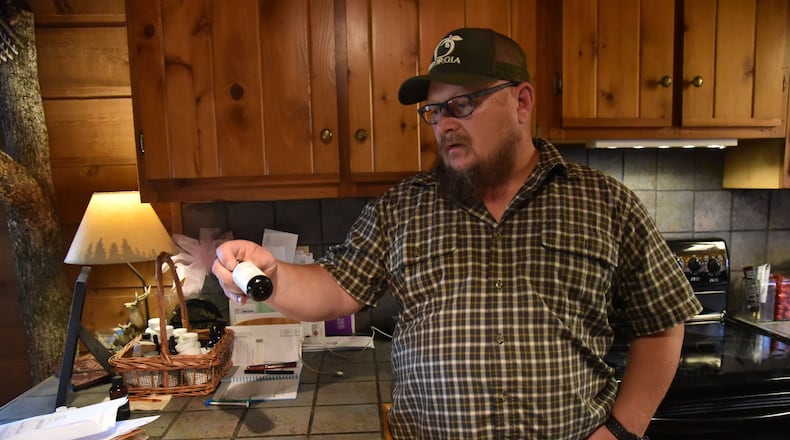 Jim Wages holds a bottle of cannabis oil for his daughter Sydney at their home in Dallas in 2017. The family was among the very first to receive permission from Georgia to use low-dose cannabis oil without fear of prosecution, but it still has no way to legally obtain the medication. "We’ve been fighting years for this, and we still don’t have anything we can go into the store and buy,” Wages said. “It’s just gotten to the point where we need to move forward with this thing.” HYOSUB SHIN / HSHIN@AJC.COM