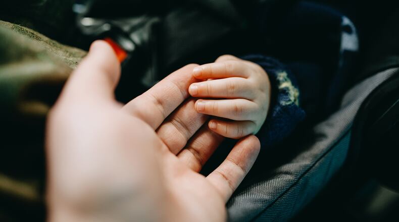 Close up of father holding baby's hand gently